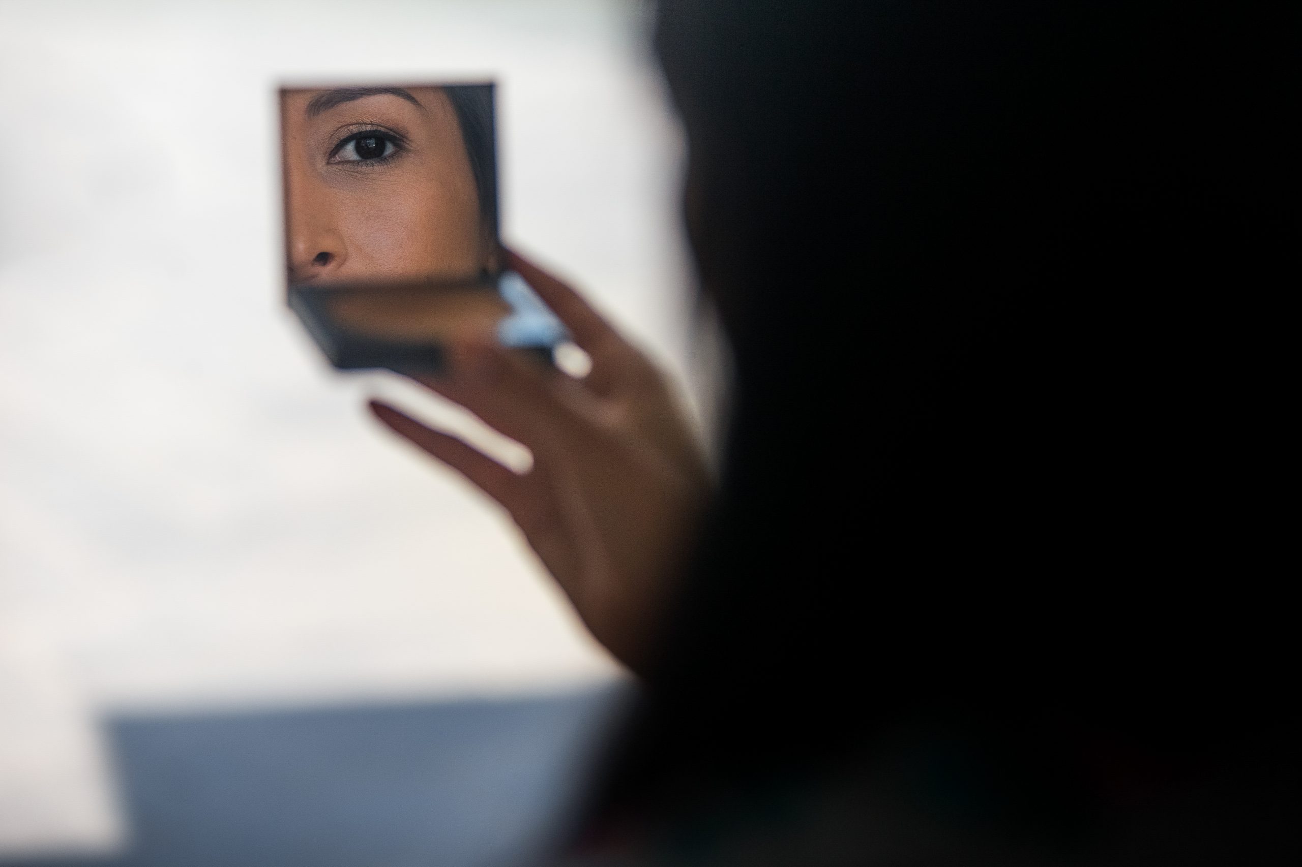 Woman looks in little mirror of her powder