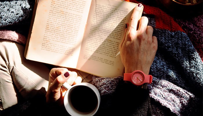 person sitting with a book and cup of coffee